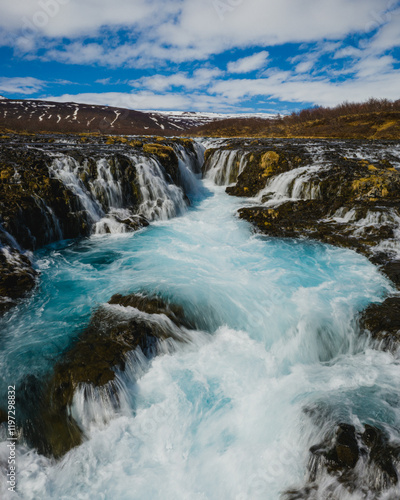 Bruarafoss waterfall with stunning turquoise waters under a bright sky in south Iceland