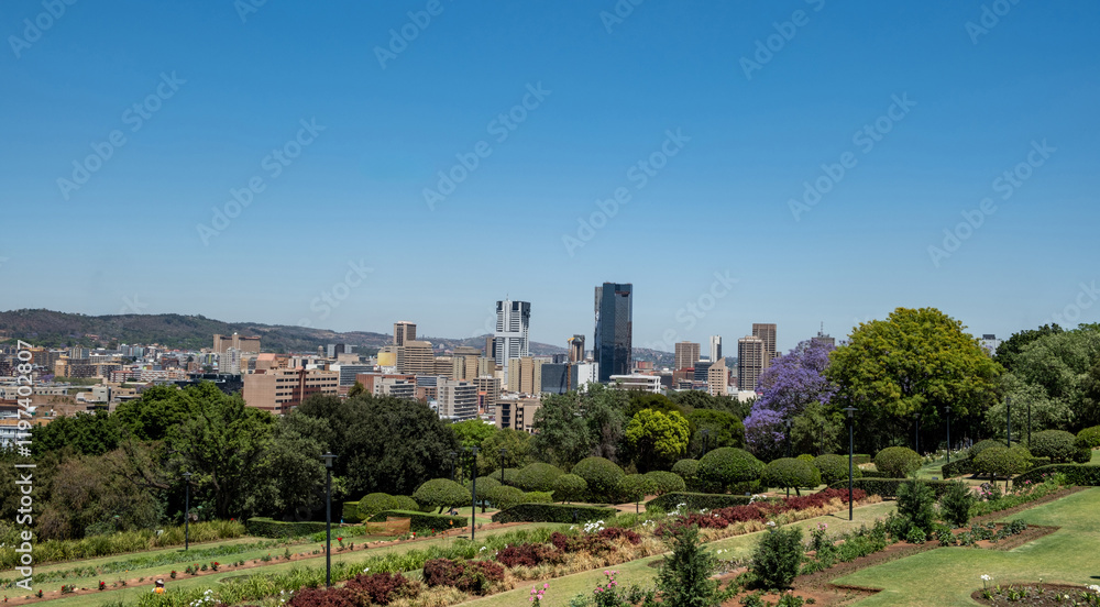 Fototapeta premium Pretoria city view from Union Buildings gardens, high buildings and blooming jacaranda trees. South Africa.