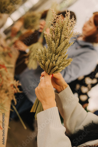 Close up of female hands hold Didukh. Master class on making Ukrainian Christmas decoration and traditional symbol. Made of straw of different cereals. Didukh literally means the spirit of ancestors photo