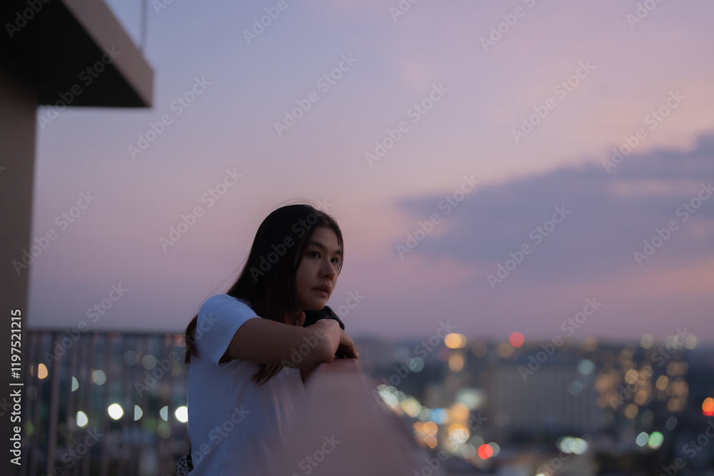 Young Asian woman leaning on a balcony railing, contemplating the illuminated cityscape at dusk, with a serene yet thoughtful expression on her face Young Asian woman leaning on a balcony railing, contemplating the illuminated cityscape at dusk, with a serene yet thoughtful expression on her face