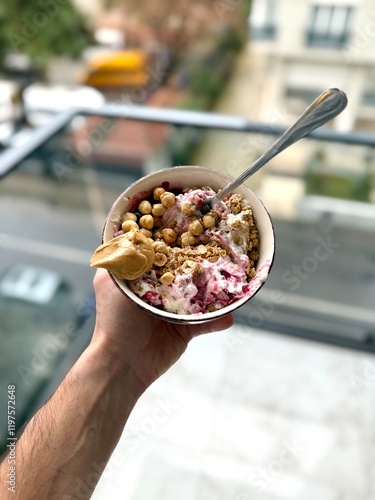 Granola with yogurt, hazelnut and jam in bowl holding in hand peanut butter