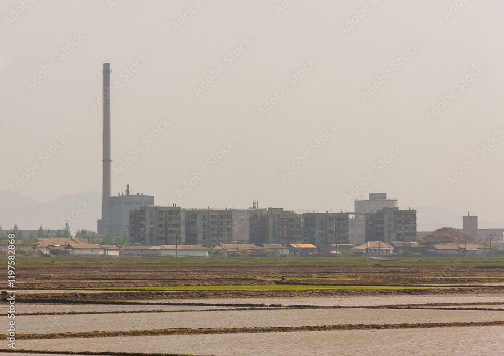 North Korean people working in a field in front of buildings and factories, Pyongan Province, Pyongyang, North Korea North Korean people working in a field in front of buildings and factories, Pyongan Province, Pyongyang, North Korea