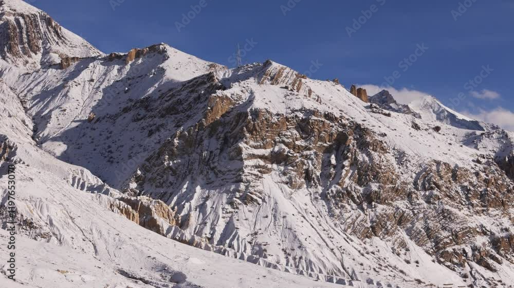Aerial shot of rugged snow-covered mountain slopes illuminated by golden sunlight Aerial shot of rugged snow-covered mountain slopes illuminated by golden sunlight