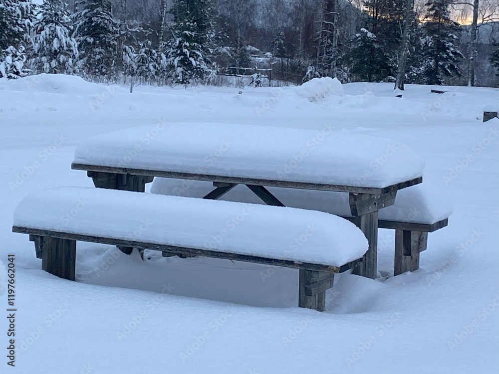 Snow-covered wooden table and benches in a beautiful Swedish landscape. Snow-covered wooden table and benches in a beautiful Swedish landscape.
