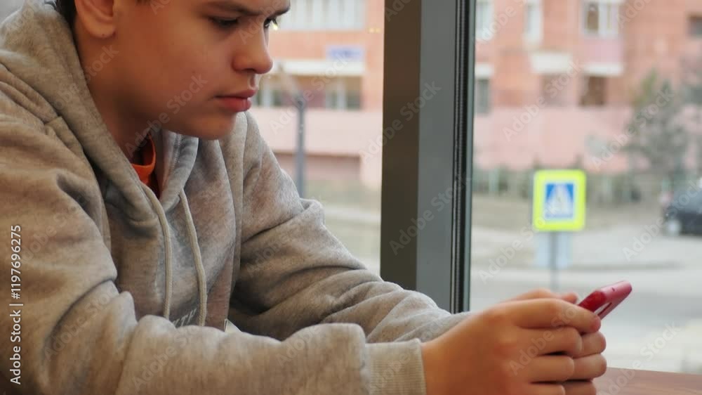 Smiling teenage gen Z boy 13-18 year old drinking coffee and holding mobile phone sitting in cafe. Happy millennial man chat with friends, or play games, social networks. Working place. Smiling teenage gen Z boy 13-18 year old drinking coffee and holding mobile phone sitting in cafe. Happy millennial man chat with friends, or play games, social networks. Working place.