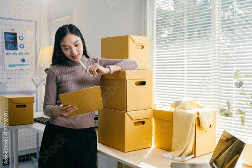 Young asian businesswoman working at home, checking order on clipboard for shipping to customer. Startup sme business concept photo