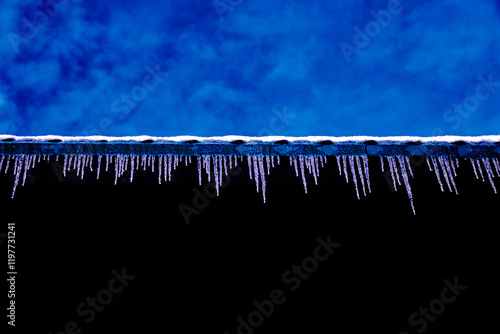 abstract blue sky with white clouds and icicles hanging on a black background reflecting the blue sky