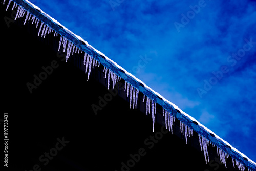 abstract blue sky with white clouds and icicles hanging on a black background reflecting the blue sky