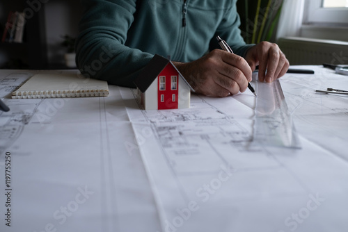 Architect man holding pencil working with laptop and blueprints for architectural plan, engineer sketching a construction project concept.