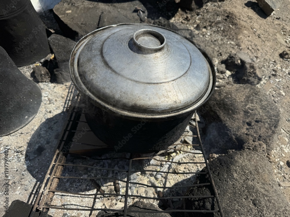 Close-up of old black cauldron. Old large cauldrons for cooking. Cauldrons and ovens in agricultural field. Seasonal agricultural workers' cooking and water heating materials. Close-up of old black cauldron. Old large cauldrons for cooking. Cauldrons and ovens in agricultural field. Seasonal agricultural workers' cooking and water heating materials.