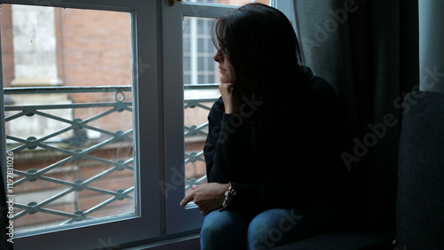 Pensive melancholical woman looking out window thinking photo