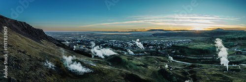 Aerial view of Hveragerdi, South Iceland, showcasing geothermal steam vents and rugged landscapes at dawn.