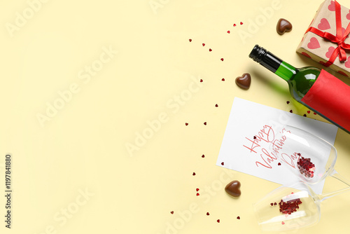 Bottle of wine with glasses, postcard and gift on yellow background. Valentine's Day celebration