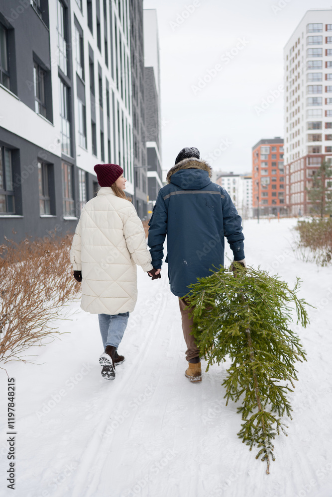 Couple Walks with Christmas Fir in Snowy Urban Landscape Couple Walks with Christmas Fir in Snowy Urban Landscape