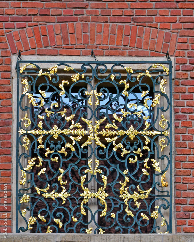ozdobna krata na okno ze złoceniami, dekoracyjna krata okienna na oknie w ceglanej ścianie, decorative grill on a window in a brick wall, gilded grille on a brick building