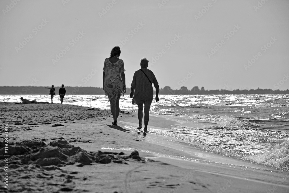 młoda kobieta i starsza kobieta idące razem plażą, kobiety idące plażą, dwie kobiety idące plażą, young woman and senior woman walking on the beach together