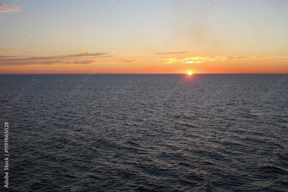 Die Sonne geht unter über dem Skagerrak an einem schönen Sommertag. Die Wellen sind dunkel, und die teils untergegangene Sonne taucht den Himmel in orangefarbenes Licht. Gesehen von einer Fähre. Die Sonne geht unter über dem Skagerrak an einem schönen Sommertag. Die Wellen sind dunkel, und die teils untergegangene Sonne taucht den Himmel in orangefarbenes Licht. Gesehen von einer Fähre.