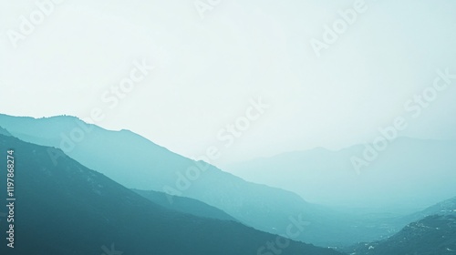 A scenic view of softly layered mountain silhouettes fading into the misty air, bathed in morning light, invoking a peaceful contemplation of natural beauty. photo