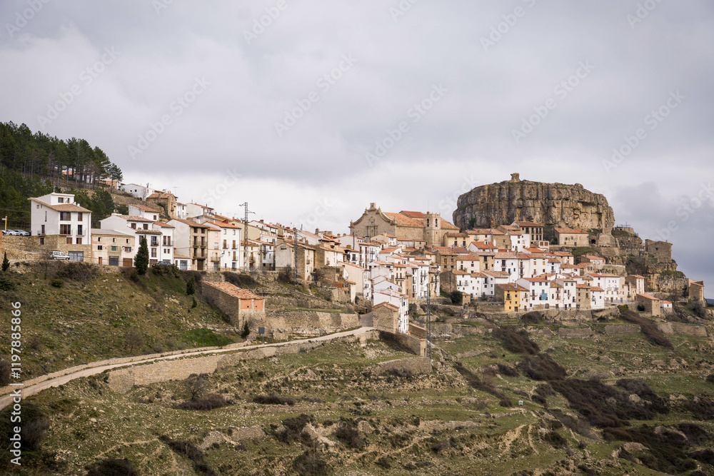 Obraz premium View of the small village of Ares del Maestre on the top of a mountain with its traditional church and the castle on the hill.