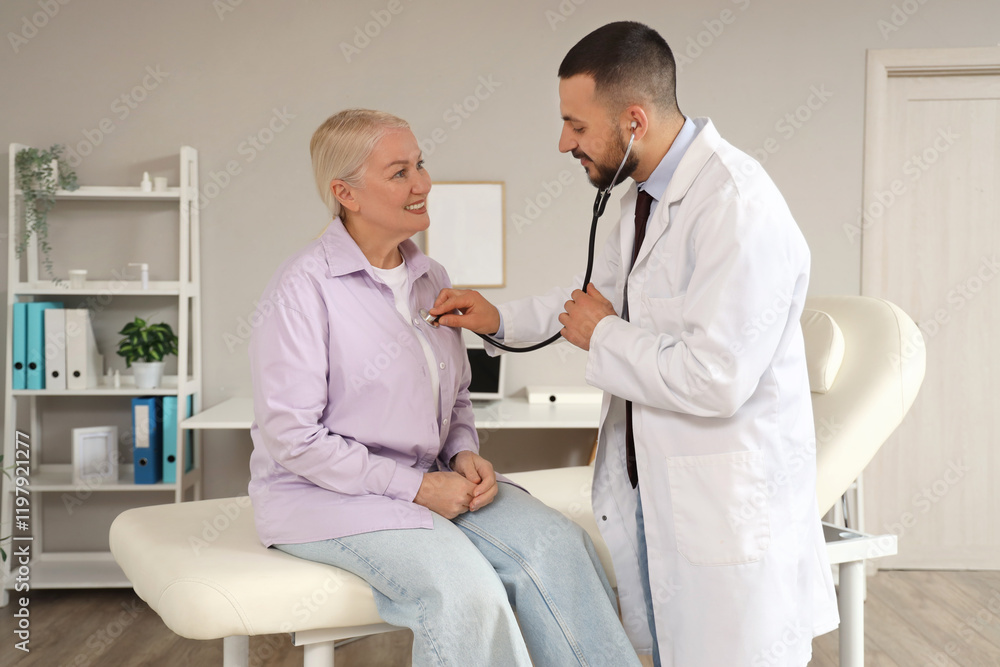 Obraz premium Male doctor with stethoscope listening to mature woman in clinic