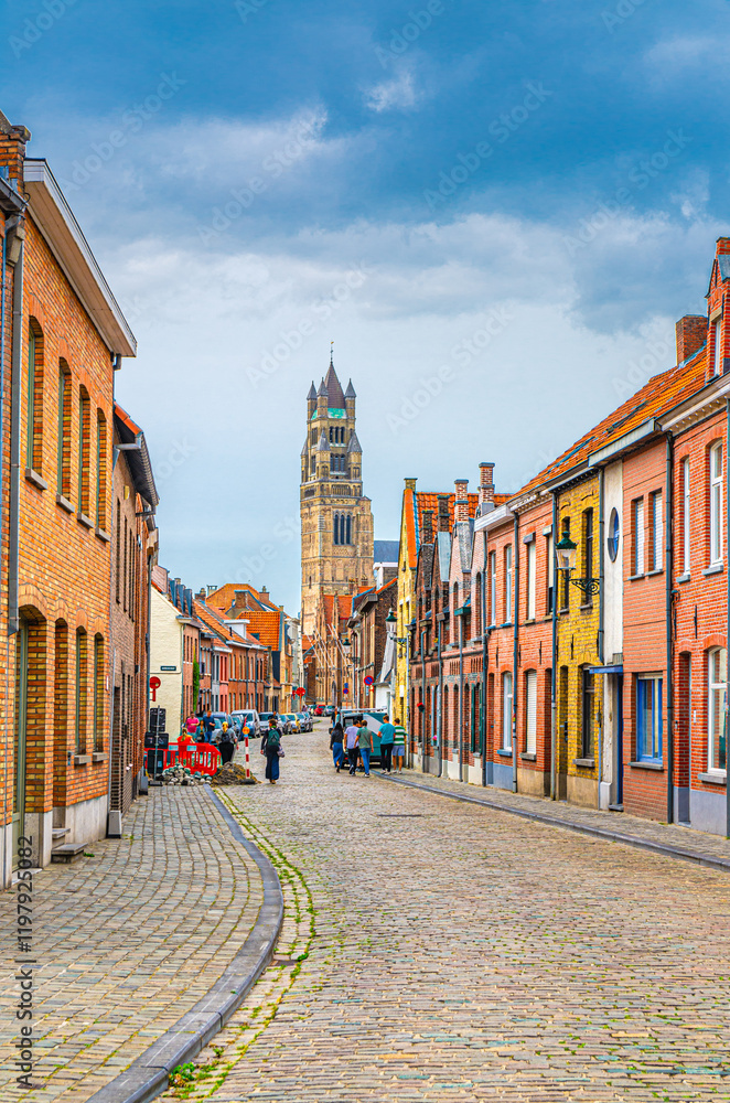 Fototapeta premium Bruges cityscape, narrow cobblestone street, colorful buildings and houses in Brugge city historical centre, Bruges old town quarter, St. Salvator's Cathedral Roman Catholic church tower, Belgium