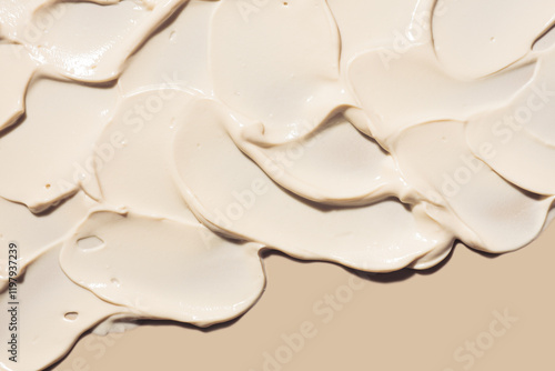 Cosmetic milky beige cream balm thick nourishing or mask texture smudge on beige background