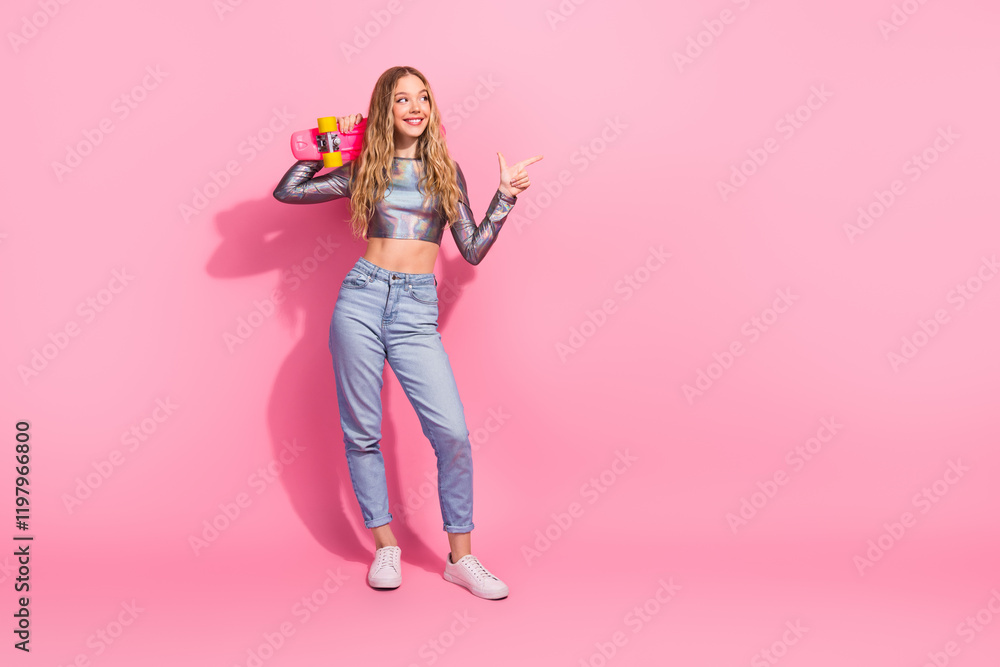 Trendy young woman in metallic top holding skateboard on vibrant pink background Trendy young woman in metallic top holding skateboard on vibrant pink background