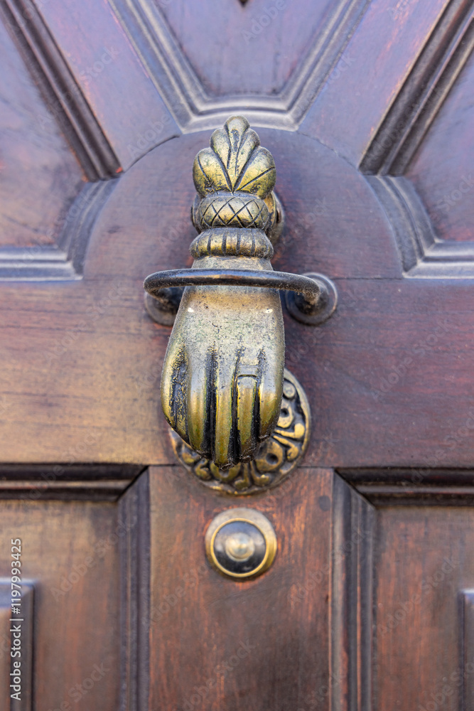 Antique brass door knocker in the shape of a hand. Antique brass door knocker in the shape of a hand.