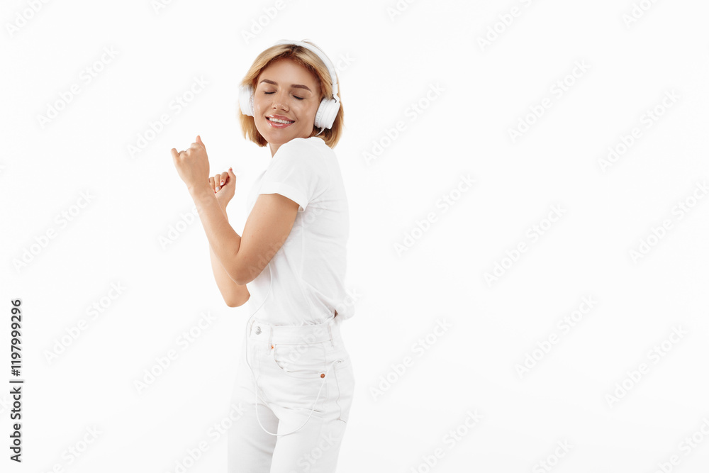 Stylish young blonde woman in casual white outfit listening music in headphones over red background. Stylish young blonde woman in casual white outfit listening music in headphones over red background.