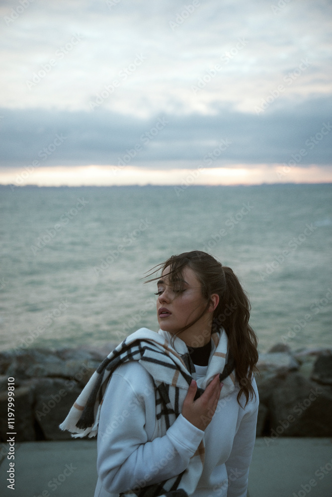 Beautiful young girl in a white tracksuit stands on the seashore in stormy weather Beautiful young girl in a white tracksuit stands on the seashore in stormy weather