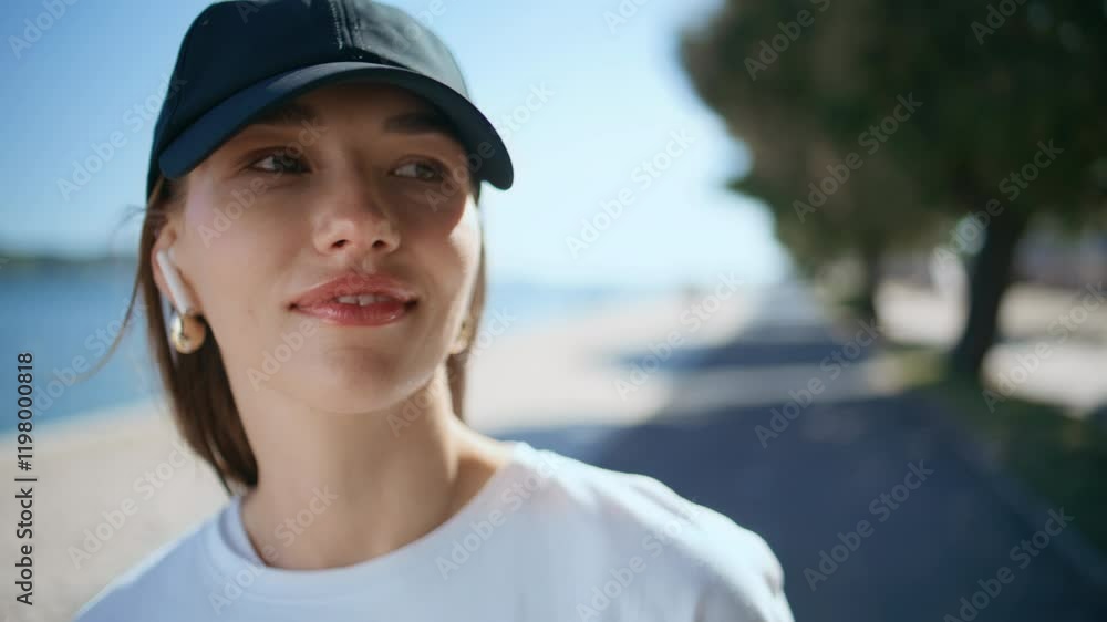 Portrait smiling woman cap standing by riverside summer morning. Girl in earbuds Portrait smiling woman cap standing by riverside summer morning. Girl in earbuds