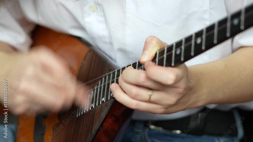 Close up woman hands strumming quickly on classic balalaika, playing quickly. Wooden acoustic string musical instrument with sound hole and frets. Performance, sound extraction, rhythm solo practicing Close up woman hands strumming quickly on classic balalaika, playing quickly. Wooden acoustic string musical instrument with sound hole and frets. Performance, sound extraction, rhythm solo practicing