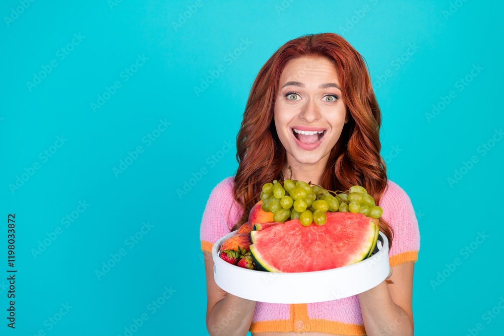 Photo portrait of lovely young lady excited hold fruits tray dressed stylish pink garment isolated on cyan color background Photo portrait of lovely young lady excited hold fruits tray dressed stylish pink garment isolated on cyan color background