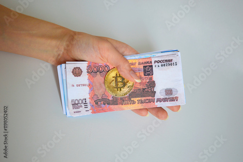 Bitcoin coin and a pack of Russian rubles in a female hand on a white background. investing in crypto coins. e-commerce, mining and blockchain photo