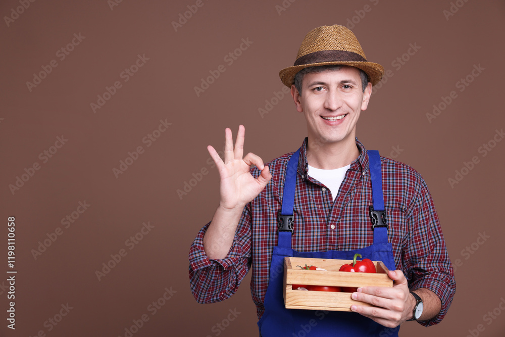 Farmer with vegetables showing okay gesture on brown background. Space for text