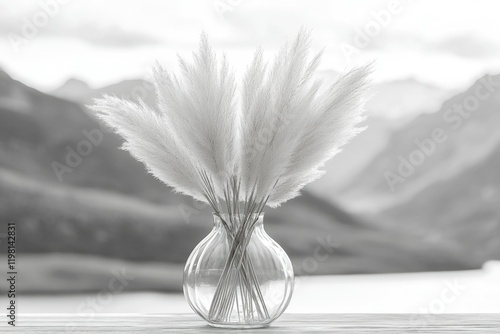 Fluffy pampas grass in a clear glass vase, set against a blurred mountain backdrop.