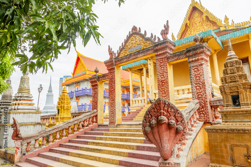 Fototapeta premium Colorful yellow buddist Monkey temple surrounded by stupas and Naga statues, Phnom Penη, Cambodia