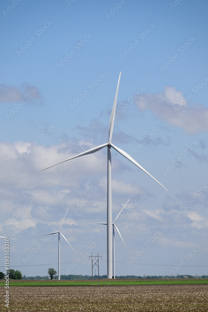 Giant white wind turbines in green field with white clouds and blue sky Giant white wind turbines in green field with white clouds and blue sky
