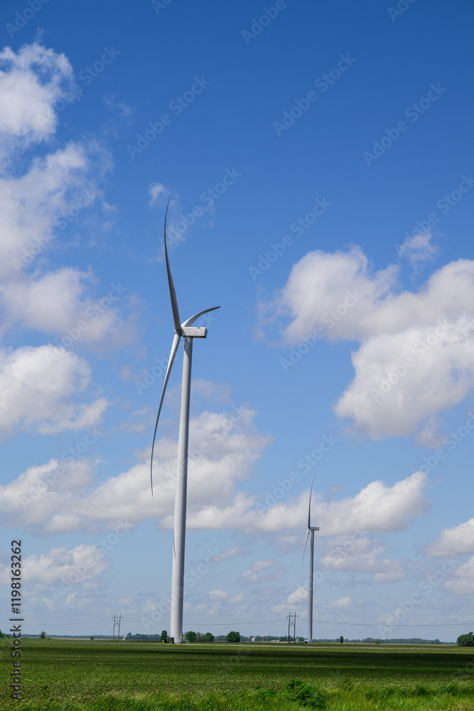 Giant white wind turbines in green field with white clouds and blue sky Giant white wind turbines in green field with white clouds and blue sky