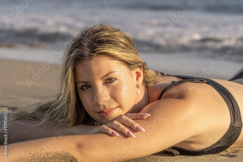 Young white woman in black bikini on the beach at sunset