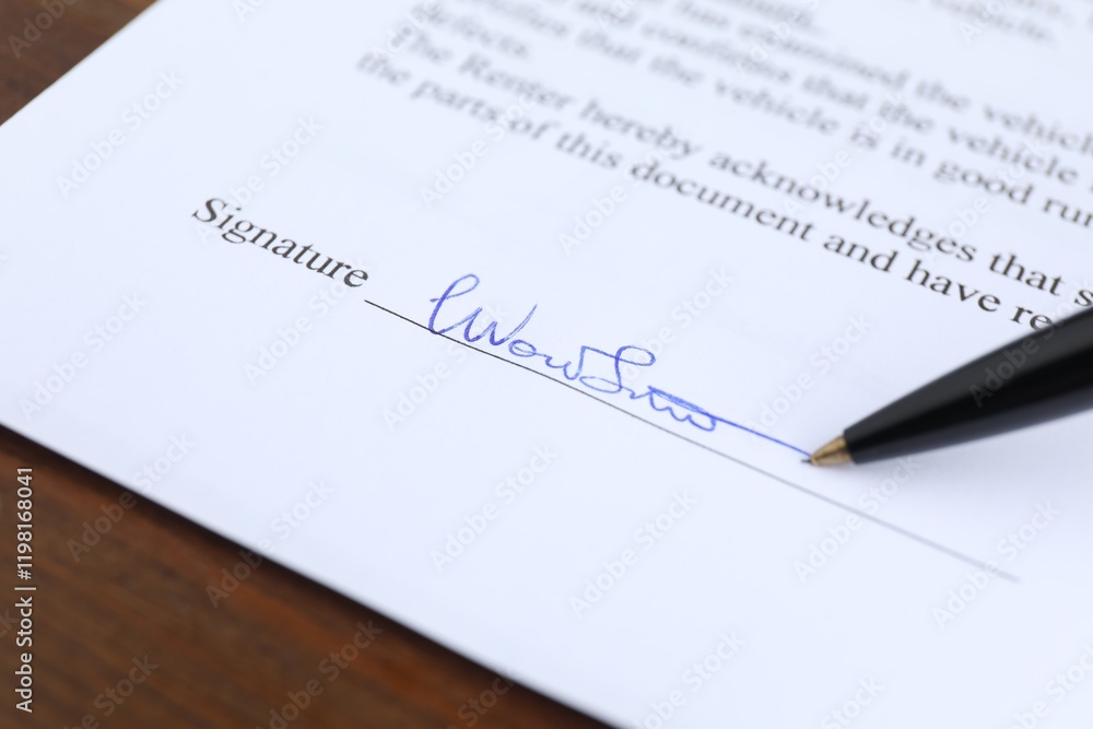 Ballpoint pen leaving signature on contract at wooden table, closeup Ballpoint pen leaving signature on contract at wooden table, closeup