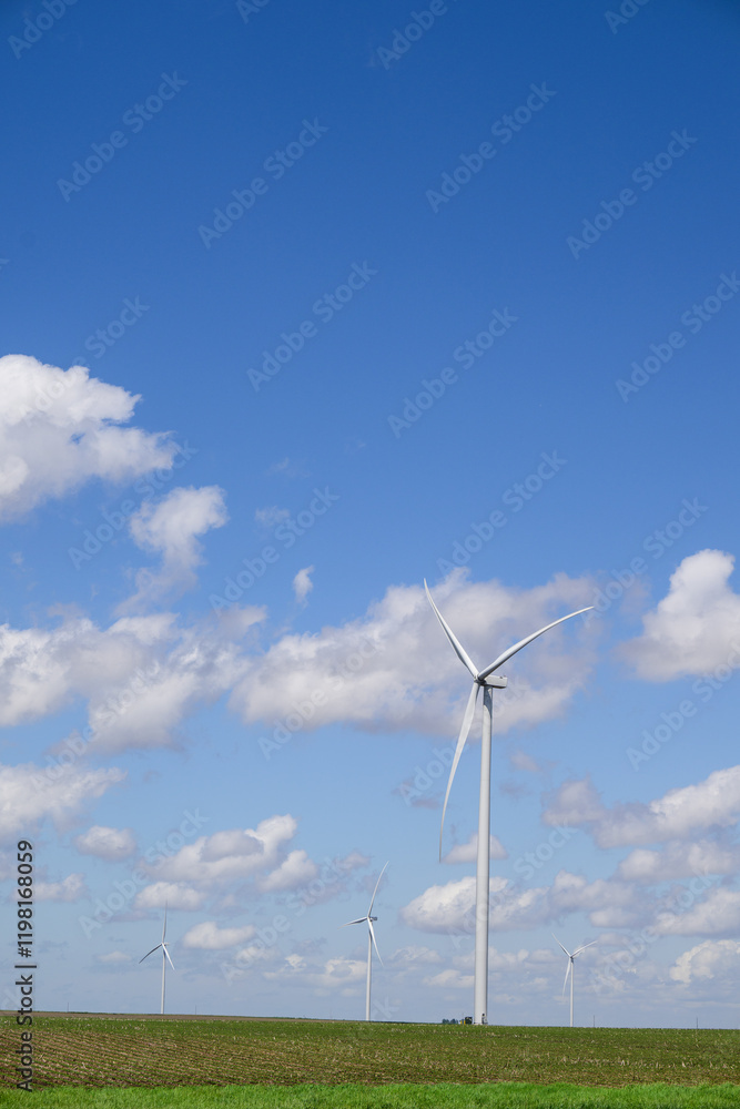 Giant white wind turbine windmill with blue sky and cumulus clouds Giant white wind turbine windmill with blue sky and cumulus clouds
