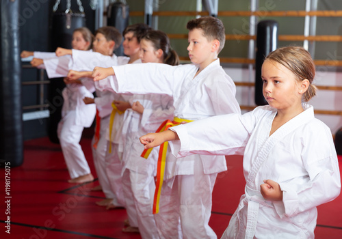 Group of young girls and boys in kimono doing kata in gym. photo