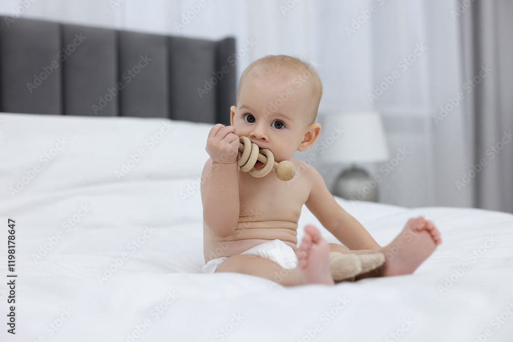 Cute little baby with rattle on bed indoors Cute little baby with rattle on bed indoors