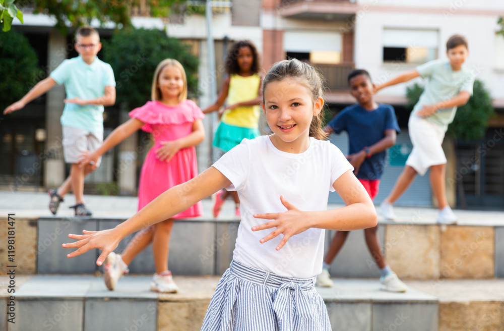 Obraz premium Modern preteen girl dancing with group of friends on city street. Urban lifestyle. Alpha generation..