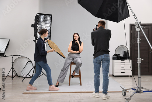 Photographer and assistant working with model in professional photo studio