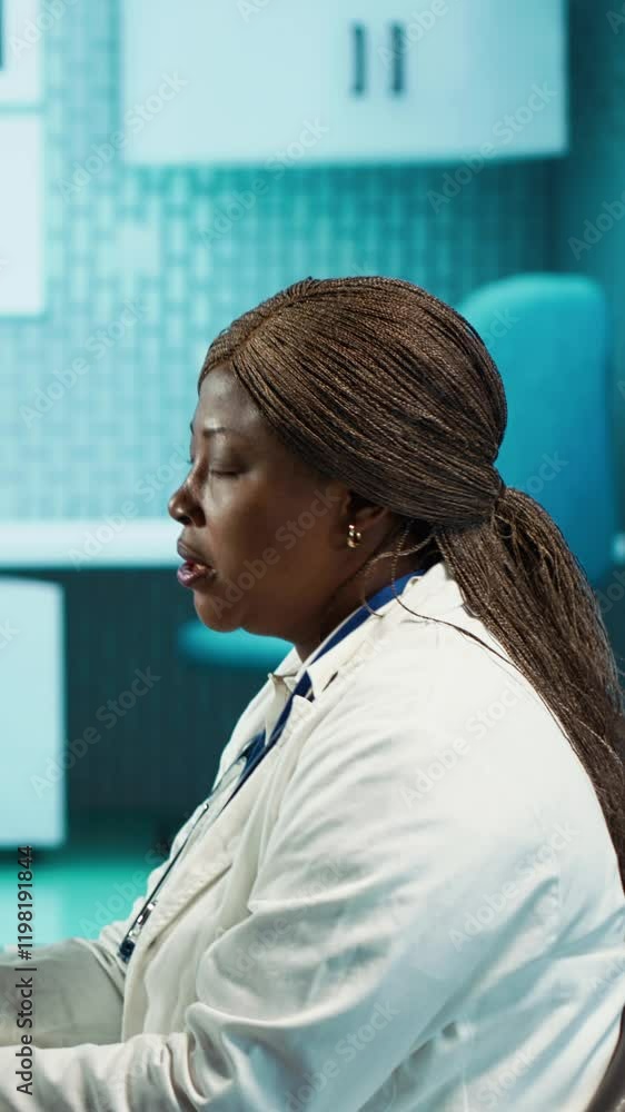 Vertical video Black general practitioner explaining clinical records and results to a patient during a health care visit, focusing on treatment advice and effective communication in a facility office