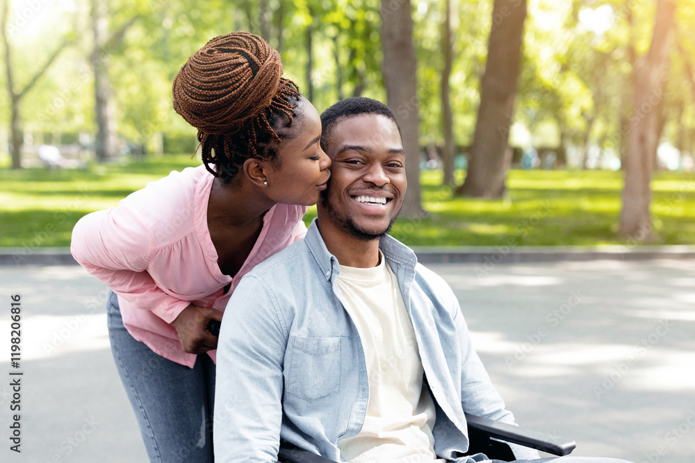 Affectionate black woman kissing her disabled husband in wheelchair, going for walk with him at city park. Young African American lady expressing love for her impaired boyfriend outdoors Affectionate black woman kissing her disabled husband in wheelchair, going for walk with him at city park. Young African American lady expressing love for her impaired boyfriend outdoors
