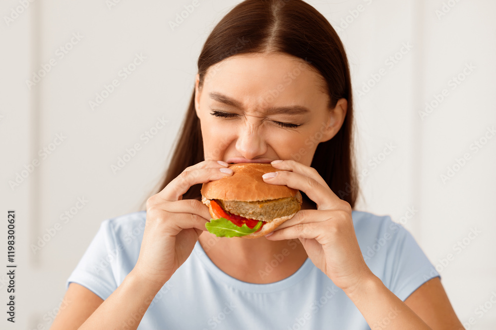 Girl Eating Burger Enjoying Fast Food Having Diet Break At Home. Cheat Meal Concept. Girl Eating Burger Enjoying Fast Food Having Diet Break At Home. Cheat Meal Concept.