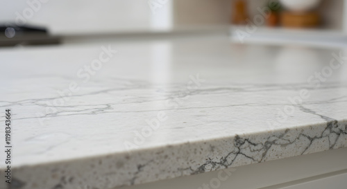 A detailed view of a white granite kitchen countertop intended for placement over a softly blurred kitchen featuring white and wooden elements.
 photo